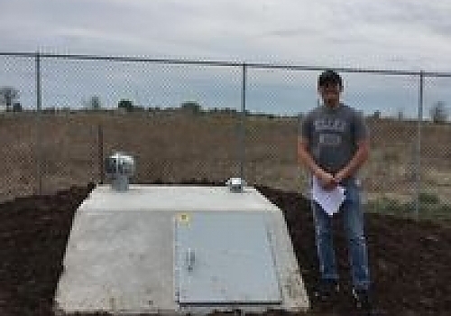 Man standing next to a storm shelter | Wainwright, OK