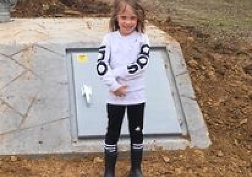 Girl standing next to a storm shelter | Texanna, OK